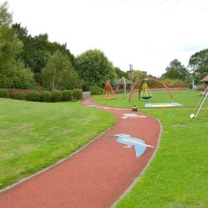 Large playground with grass, paths and playground equipment.