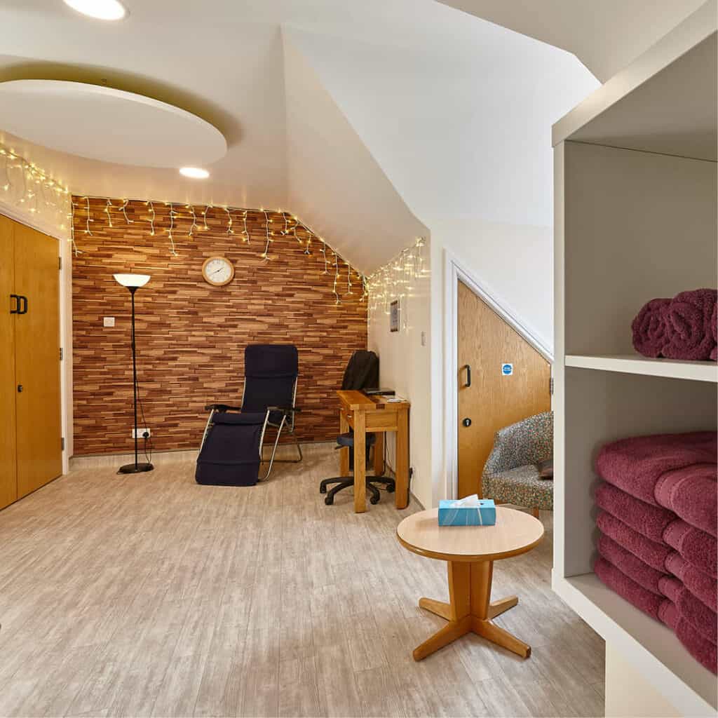 A bright therapy room with towels, massage bed and atmospheric lighting