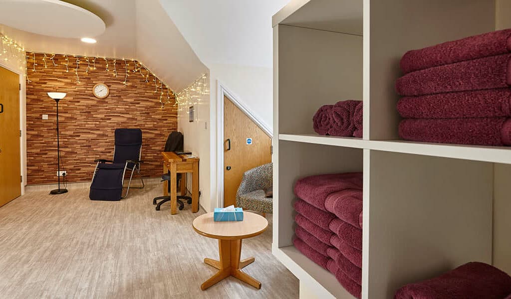 A bright therapy room with towels, massage bed and atmospheric lighting