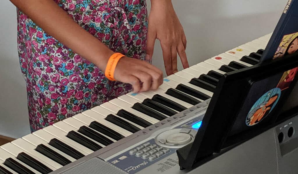 Close up of piano keyboard with a girls hand playing the keys