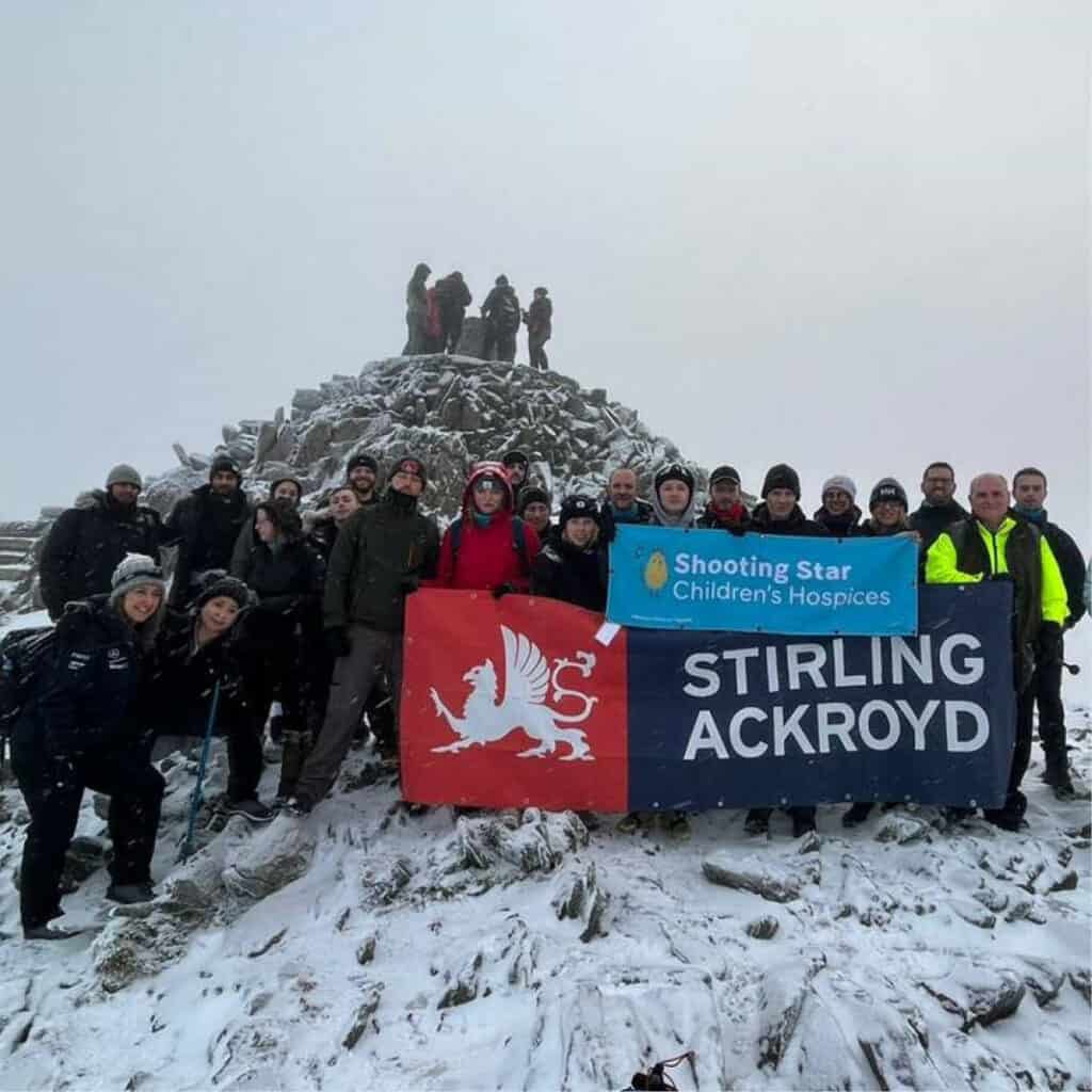 A grey and snowy picture of group of hikers at the top of Mount Snowdon