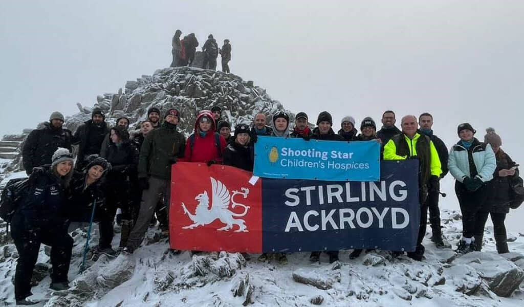 A grey and snowy picture of group of hikers at the top of Mount Snowdon