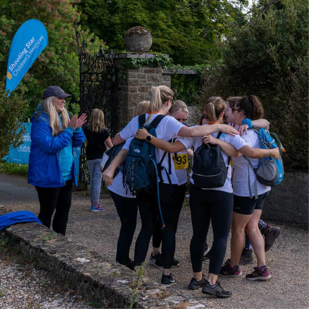 Group of women hug in a circle celebrating completing the Sunrise Walk