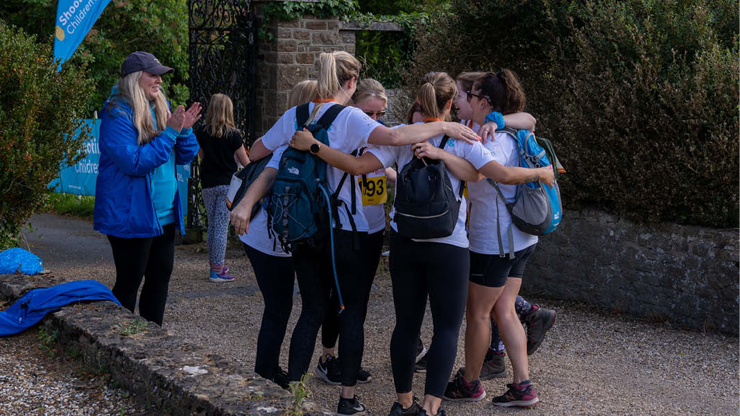 Group of women hug in a circle celebrating completing the Sunrise Walk