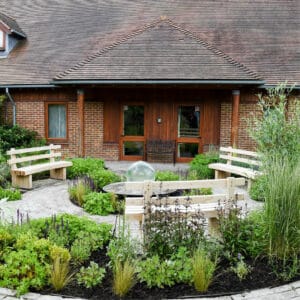 Calm circular memory garden with benches facing toward water feature and sensory plants including lavender and grasses