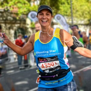 Woman running in blue and yellow Shooting Star Children's Hospices branded running vest