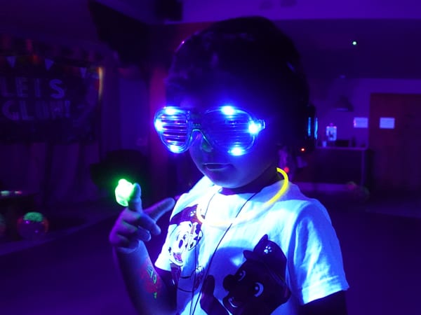 A supported child wearing glowing goggles at our GLOW event