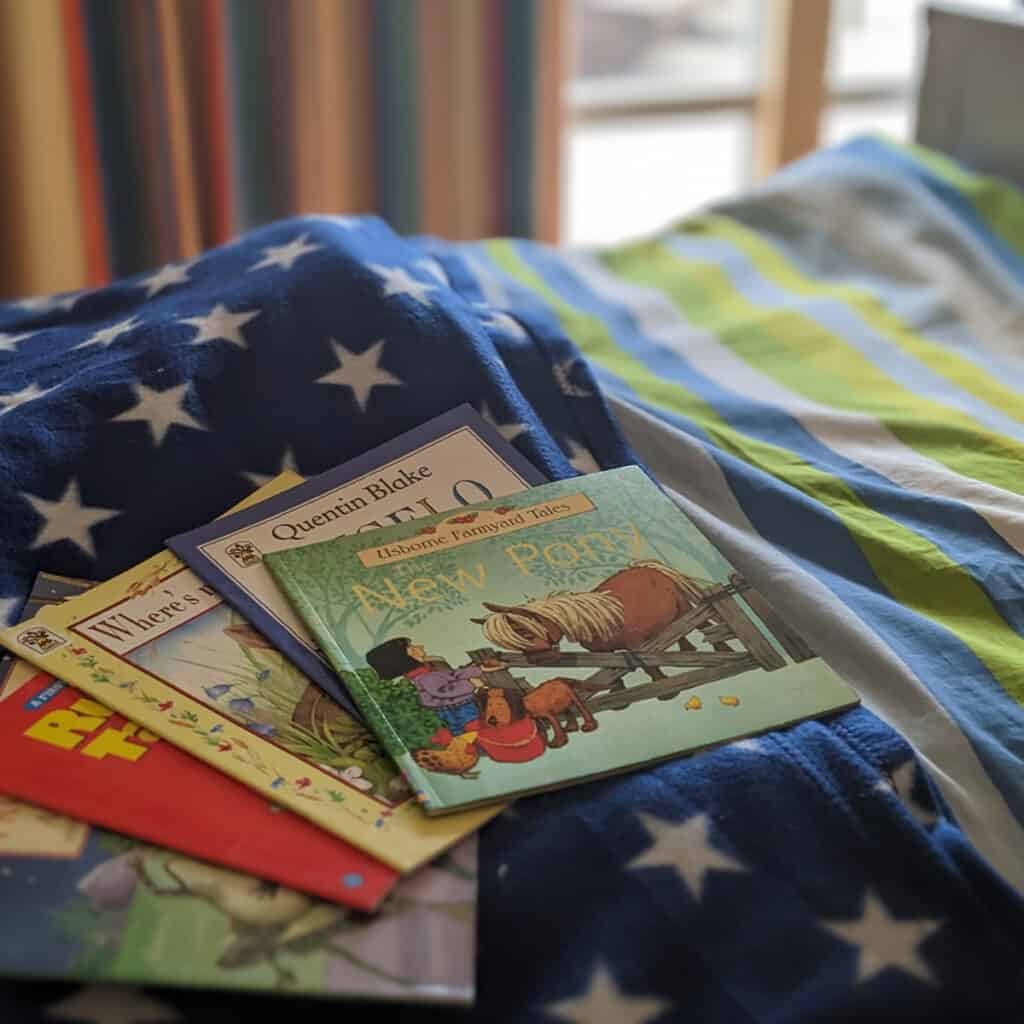 a small pile of children's books on a hospital bed