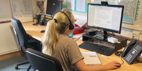 A symptom care nurse on a call at her desk, with a map of our catchment area in front of us.