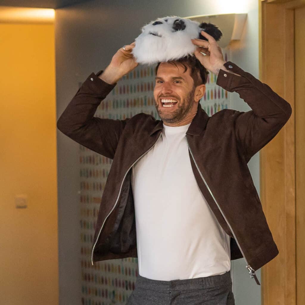 Joel Dommett lifting a Panda mask to reveal his face