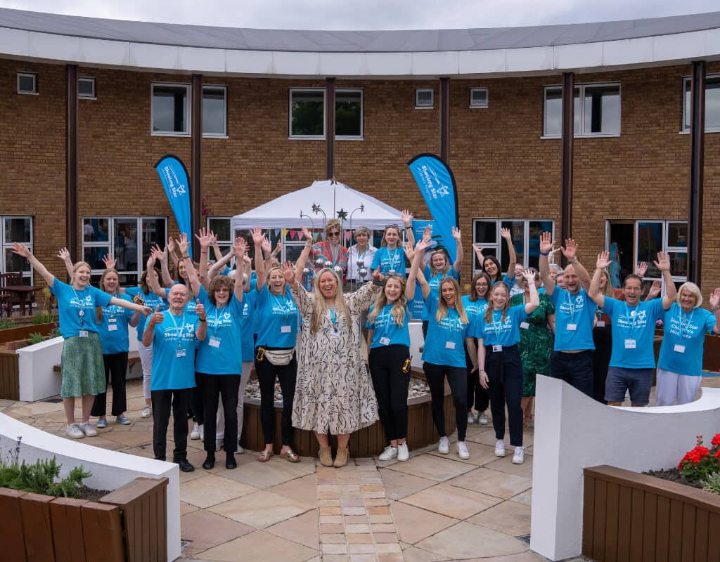 A group of staff smiling and waving at our hospice open day