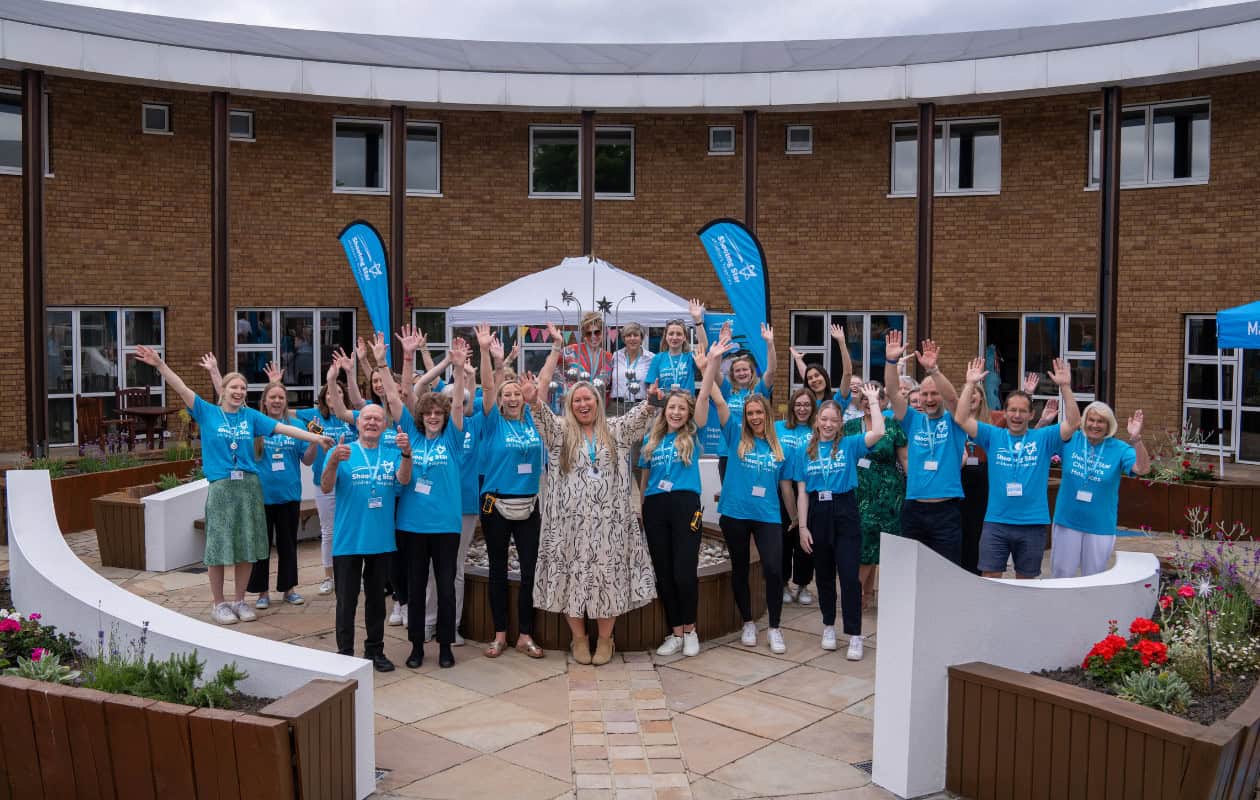 A group of staff smiling and waving at our hospice open day