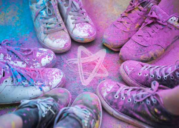 Five pairs of shoes in a circle, covered in colourful dust from a colour in