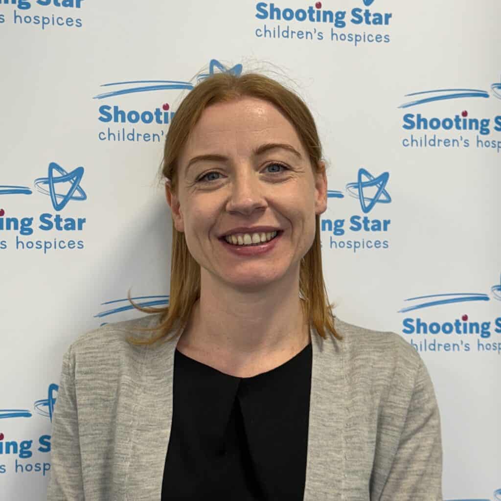A woman standing in front of a wall with a shooting star logo.
