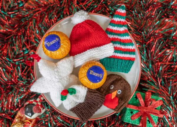 A selection of knitted novelties and chocolates on a plate.