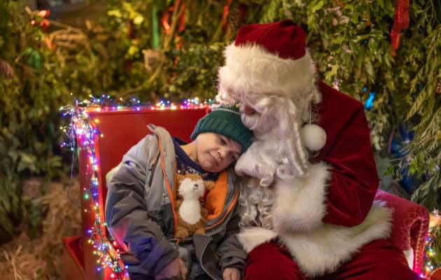 A supported child resting their head on Santa's shoulder