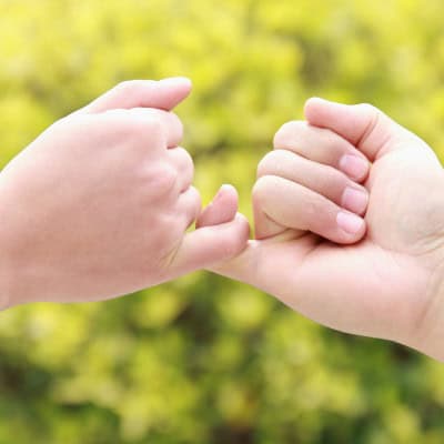 Two hands making a pinky promise with their little fingers